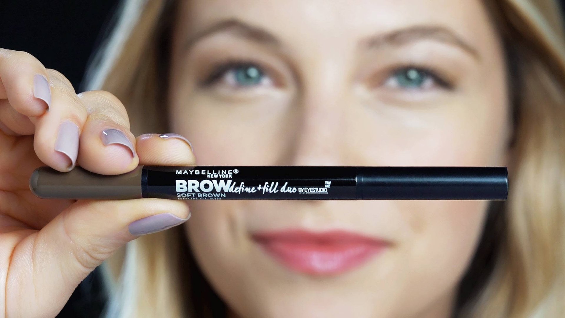 Fokus på Maybelline Brow Define og udfyldningsduo-produkt, holdt af en blond kvinde 